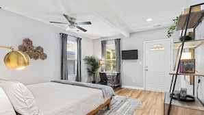 A bedroom with a bed, a ceiling fan, a desk with a chair, a TV, and a bookshelf. - Columbus Park Upper Apt Minutes from Downtown KC (Kansas City)