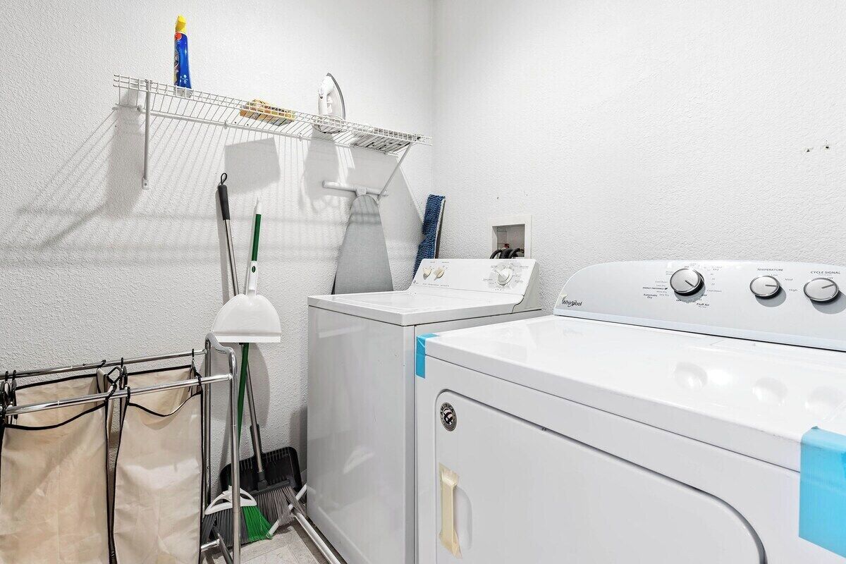 Un cuarto de lavandería con lavadora, secadora, tendedero y lavabo.