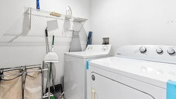 Un cuarto de lavandería con lavadora, secadora, tendedero y lavabo.