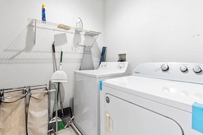 Un cuarto de lavandería con lavadora, secadora, tendedero y lavabo.
