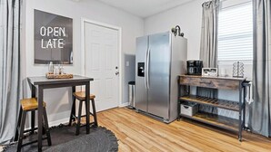 A compact kitchen with a refrigerator, a coffee maker, and a small table with stools. - Columbus Park Upper Apt Minutes from Downtown KC (Kansas City)