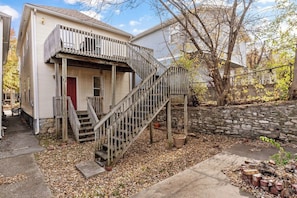 Une maison à deux étages avec un escalier en bois menant à la porte d’entrée.