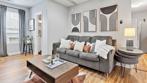 A modern living room with a grey sofa, a wooden coffee table, and abstract wall art.