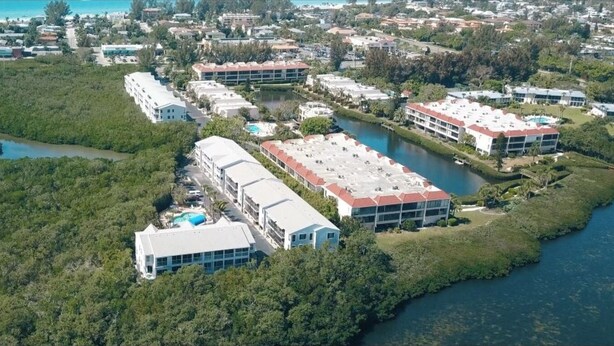 Luchtbeeld van een kusthotel met meerdere gebouwen, een groot zwembad en een jachthaven.