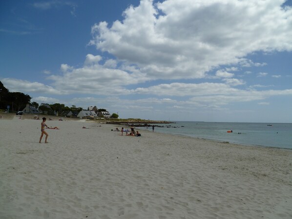 A beach with people sunbathing and swimming, a few houses in the background, and a clear sky. - Armor" apartment in 18th century house 5 min. from sandy beaches (Carnac)