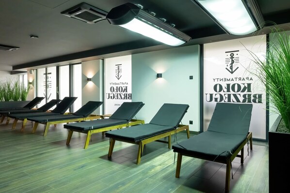A room with sun loungers, a wall with text, and a plant.