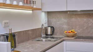 A modern kitchen with a marble countertop, stainless steel sink, and a bowl of fruit. - Salve Luxury Apartment by Litto (Split)