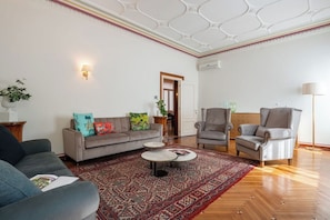 Ein Wohnzimmer mit einer Couch, Sesseln, einem Couchtisch und einem gemusterten Teppich.