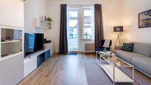Un salon moderne doté d’un téléviseur à écran plat, d’un canapé, d’une table basse et offrant une vue sur l’extérieur grâce à une grande fenêtre.