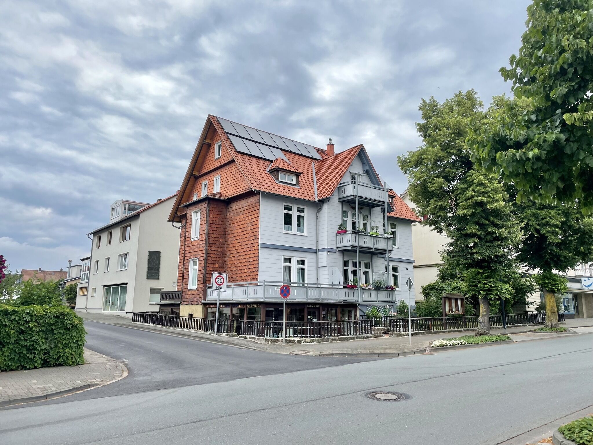 A two-story building with a red-tiled roof and a balcony.