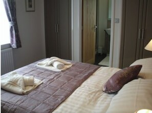 Ein ordentlich bezogenes Bett mit einer braunen Bettdecke, einem weißen Handtuch und einem braunen Kopfkissen.