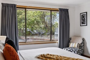 Ein Schlafzimmer mit großem Fenster, einem Bett, einem Sessel und einer Lampe.