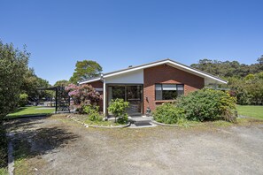 A modern two-story house with a brick facade, a large garage door, and a well-maintained garden with various plants and shrubs.