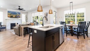 A modern kitchen with a central island, black cabinetry, and pendant lighting.