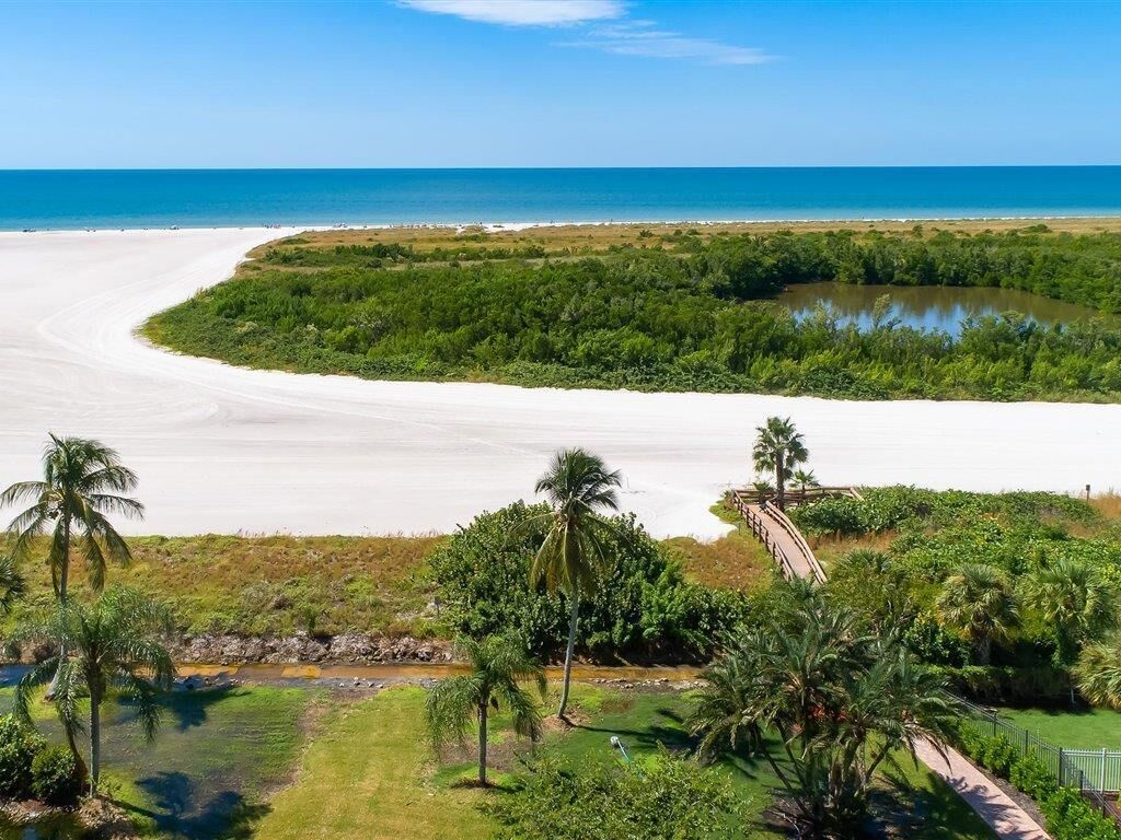 A coastal landscape with a sandy beach, a small water body, and dense greenery.