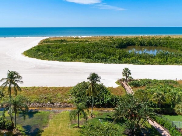 Un paysage côtier caractérisé par une plage de sable, un petit plan d’eau et une végétation luxuriante.