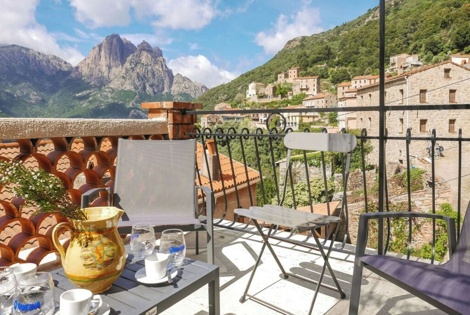 Ein Balkon mit einem Tisch für zwei Personen, einem Stuhl und einer dekorativen Vase.