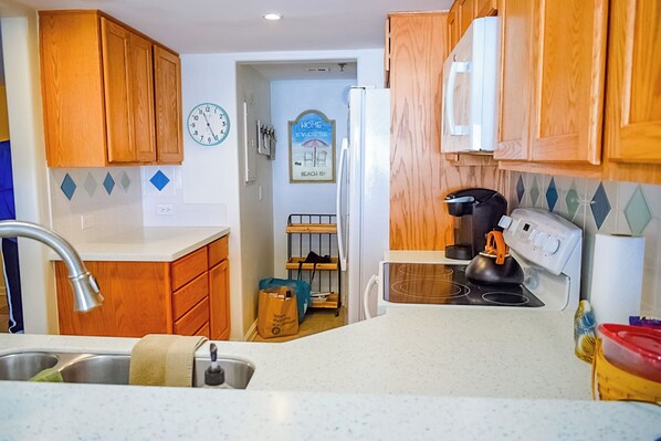 Una cocina compacta con armarios de madera, un lavabo, una estufa y un refrigerador.