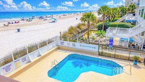 A swimming pool with a view of a beach and palm trees.