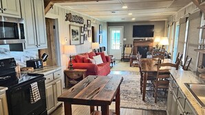 A kitchen with a red couch, wooden table, and a sign that reads "Island Queen". - Humble Heaven - Beachfront - Island Realty (Grand Isle)