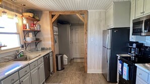 A kitchen with wooden cabinets, a stainless steel refrigerator, and a black stove. - Humble Heaven - Beachfront - Island Realty (Grand Isle)