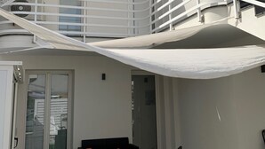Een modern gebouw met balkon, een schuifdeur van glas en buitenmeubilair.
