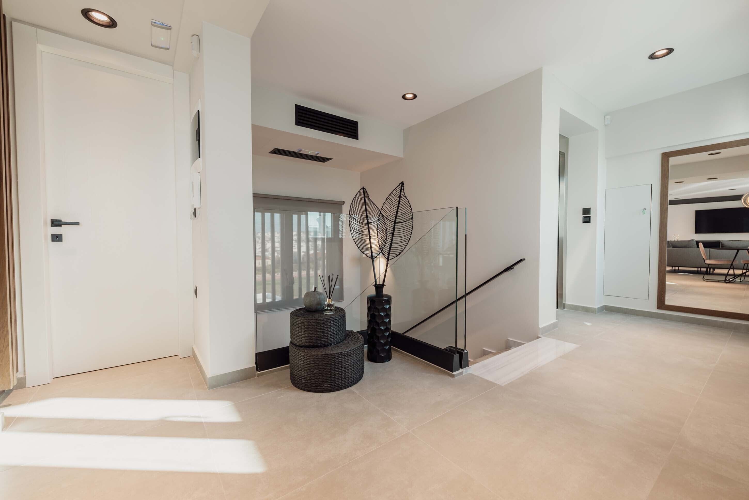 A modern interior with a staircase, a glass railing, and a minimalist decor.