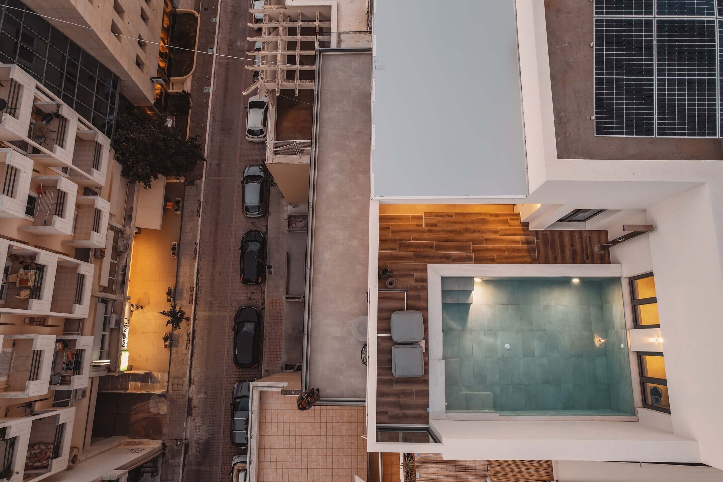 A modern building with a rooftop pool, multiple balconies, and a street view.