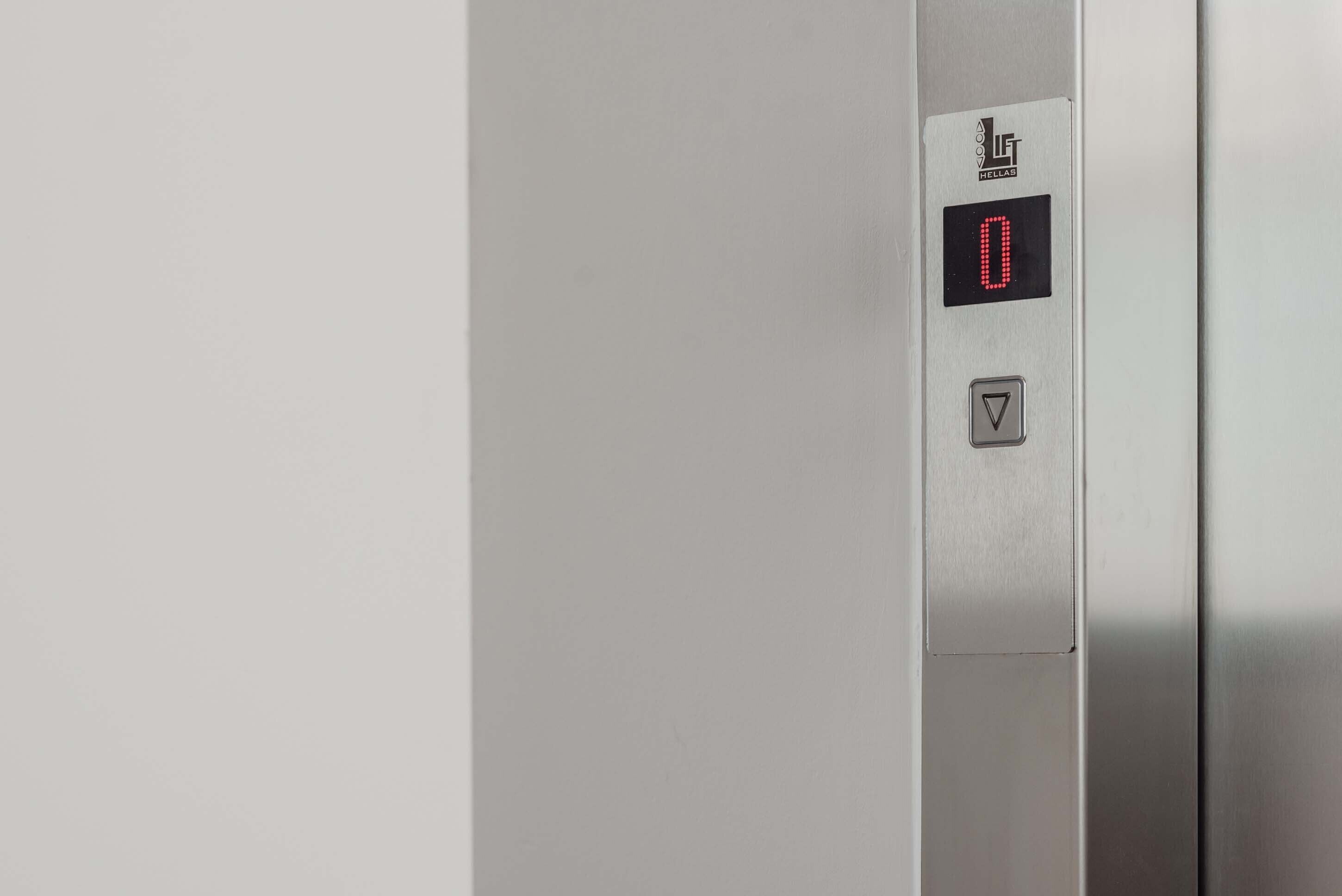 A metallic elevator control panel with a digital display showing '0' and a downward-pointing arrow.