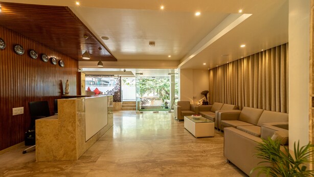A modern hotel lobby with a reception desk, seating area, and a view of the outdoors. - Tetrad Hotel - International Airport Road Hebbal (Bengaluru)