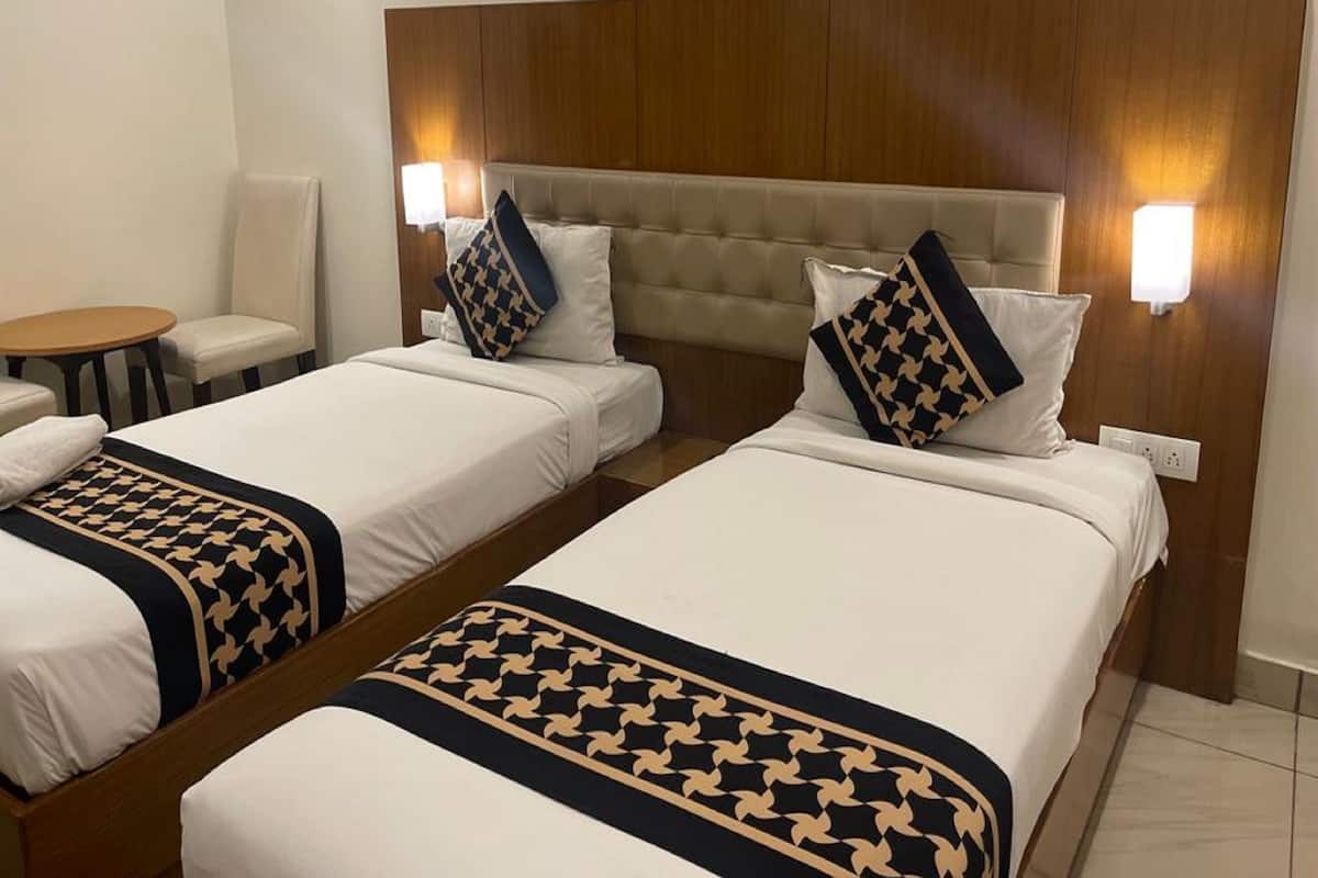 Una habitación de hotel con dos camas, una mesita pequeña y dos sillas.