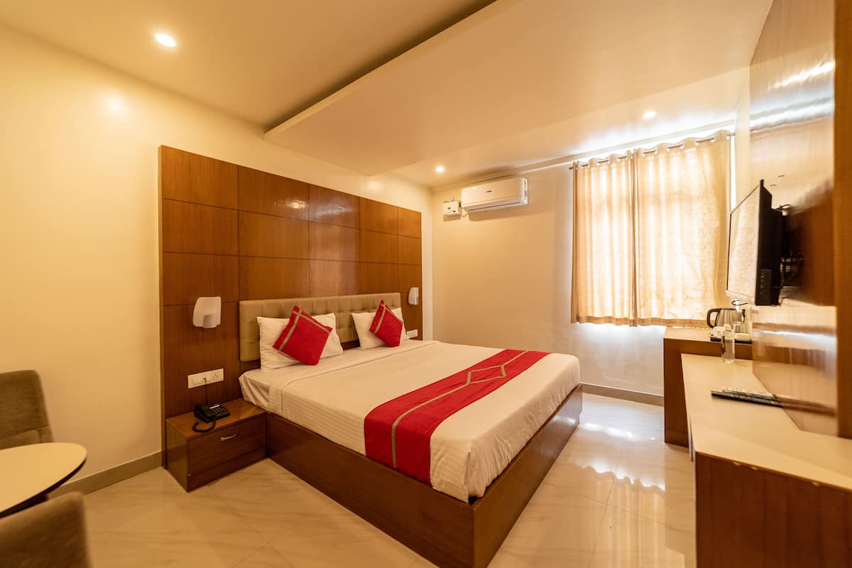 Una habitación de hotel moderna con una cama grande, una mesita de noche y un escritorio con silla.