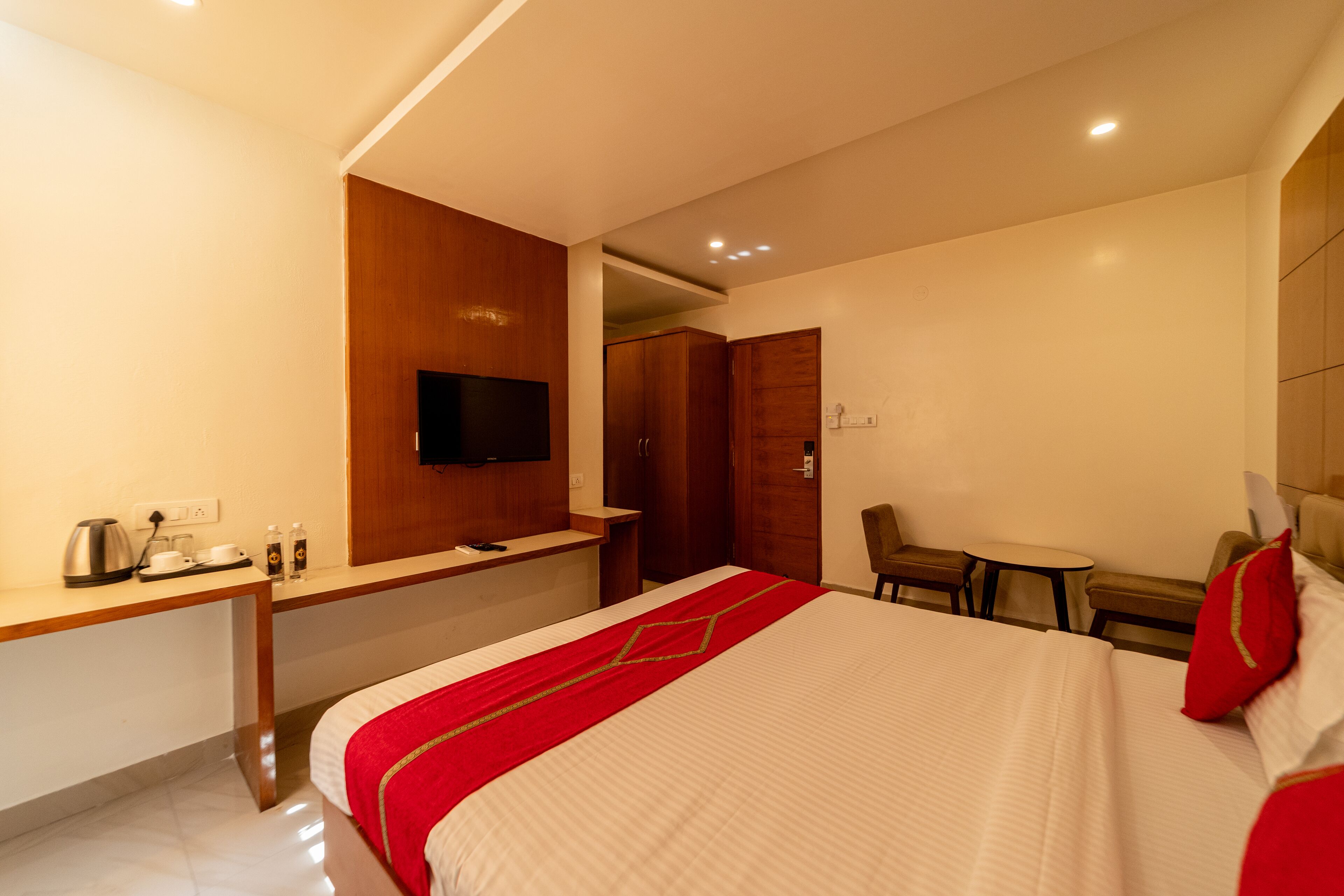 Ein Hotelzimmer mit einem Bett, einem Schreibtisch mit Fernseher, einem kleinen Tisch und einem Stuhl.