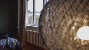 Ein Zimmer mit großem Fenster, Heizkörper und einem Bett mit gestreifter Decke.