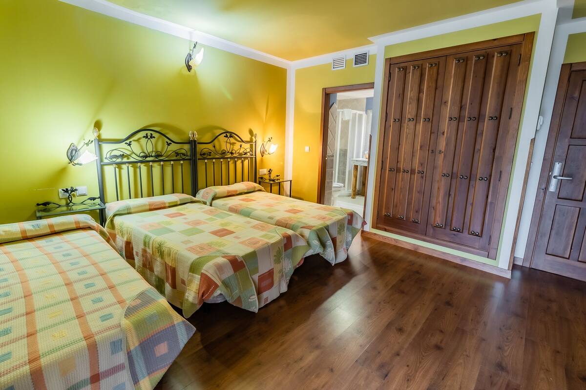 A room with two beds, wooden flooring, and a large wardrobe.