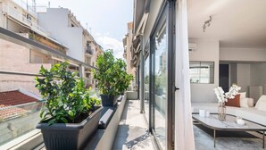 A balcony with potted plants, a sofa, and a coffee table. - Modern Oasis Build on Acropolis Ruins Free Parking (Athina)