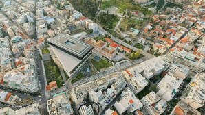 An aerial view of a city with a prominent ancient fortress on a hill, surrounded by modern buildings and a large stadium. - Modern Oasis Build on Acropolis Ruins Free Parking (Athina)
