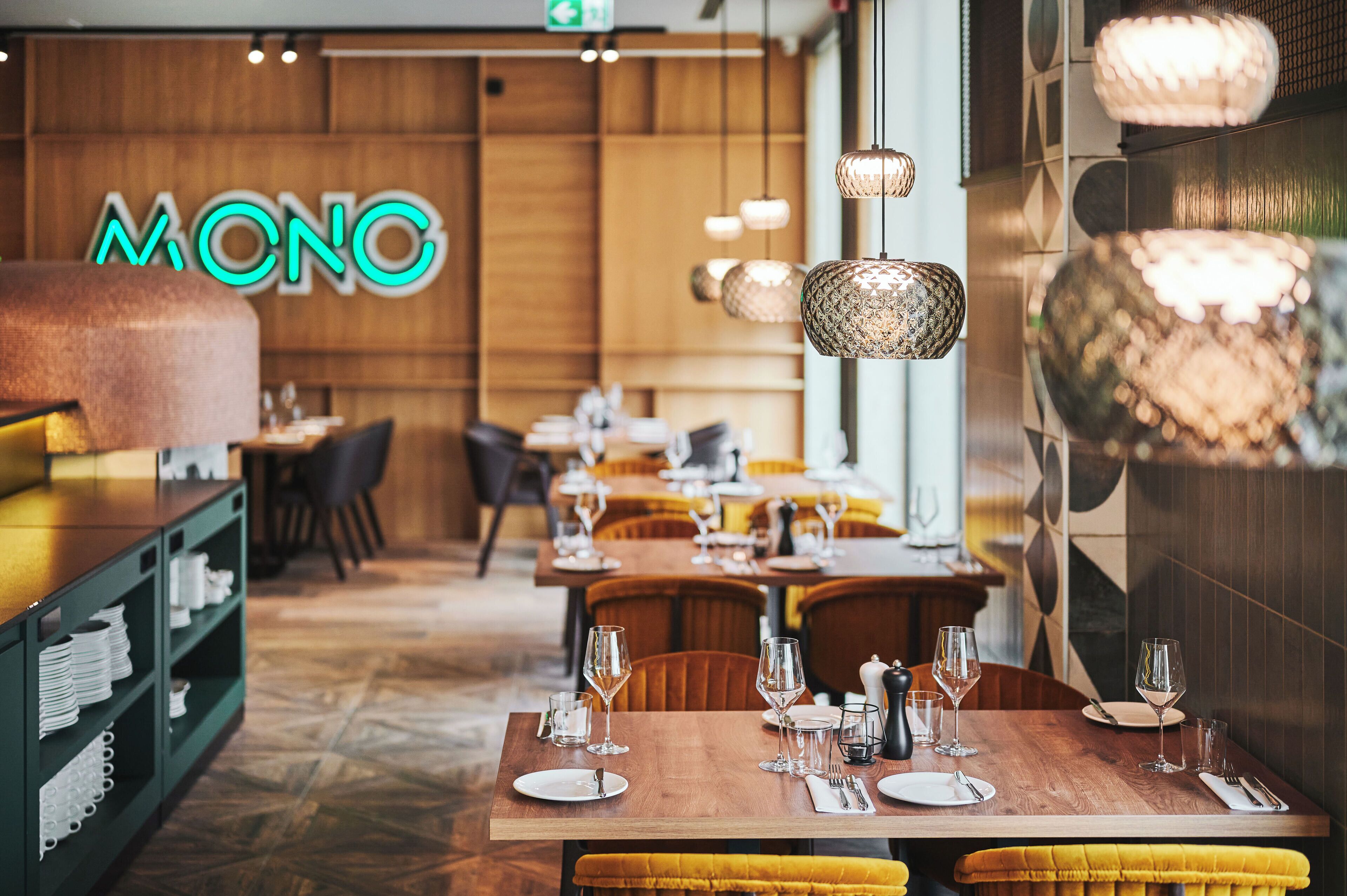 A restaurant interior with wooden walls, a neon sign, and tables set for dining.
