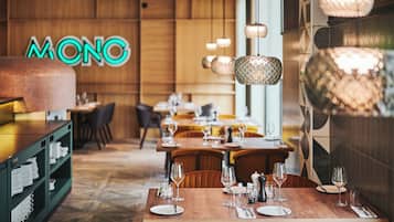 A restaurant interior with wooden walls, a neon sign, and tables set for dining.