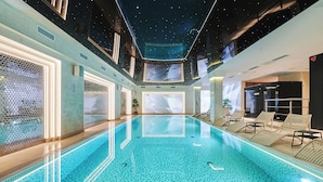 A modern indoor swimming pool with a starry ceiling, clear poolside lounge chairs, and a view of the sky through a large window. - Stay inn Hotel Warszawa  (Warsaw)