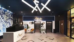 A hotel reception area with a modern design, featuring a reception desk, two chairs, a large illuminated sign, and a map on the wall. - Stay inn Hotel Warszawa  (Warsaw)