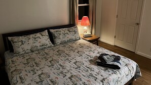 A neatly made bed with patterned bedding, a bedside lamp, and a small table with a tissue box.