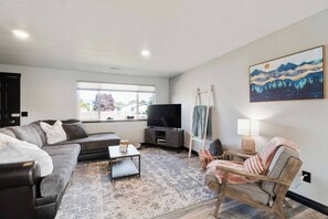A living room with a sofa, a coffee table, a TV, a ladder, a chair, and a painting on the wall. - This house is a 3 bedroom(s), 1 bathrooms, located in Enumclaw, WA. (Enumclaw)
