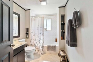A bathroom with a toilet, sink, shower curtain, bathtub, and towels. - This house is a 3 bedroom(s), 1 bathrooms, located in Enumclaw, WA. (Enumclaw)