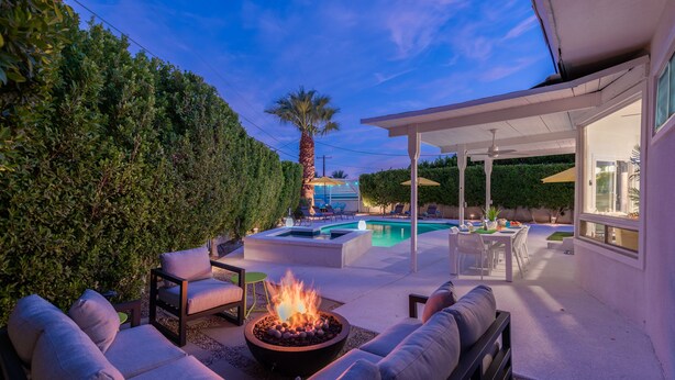 An outdoor patio with a fire pit, seating area, and a pool.