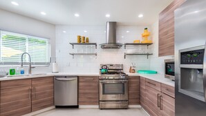 A modern kitchen with stainless steel appliances, wooden cabinets, and white tiled backsplash.