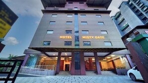Un hotel moderno llamado "Misty Gate" con una fachada simétrica, ventanas amplias y una entrada central.