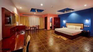 Habitación de hotel con cama, escritorio, sillas y ventilador de techo.