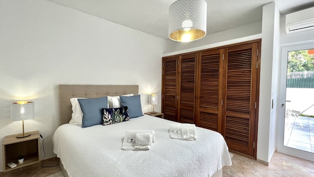Een slaapkamer met een groot bed, een houten garderobe en een hanglamp.