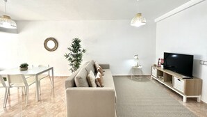 Een moderne woonkamer met een bank, televisie en een eethoek.